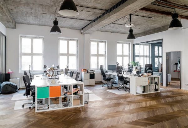 Modern office space with desks, chairs and computer, with natural light coming though window.