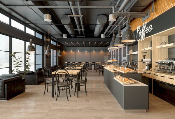 Empty Coffee Shop Interior With Wooden Tables, Coffee Maker, Pastries And Pendant Lights